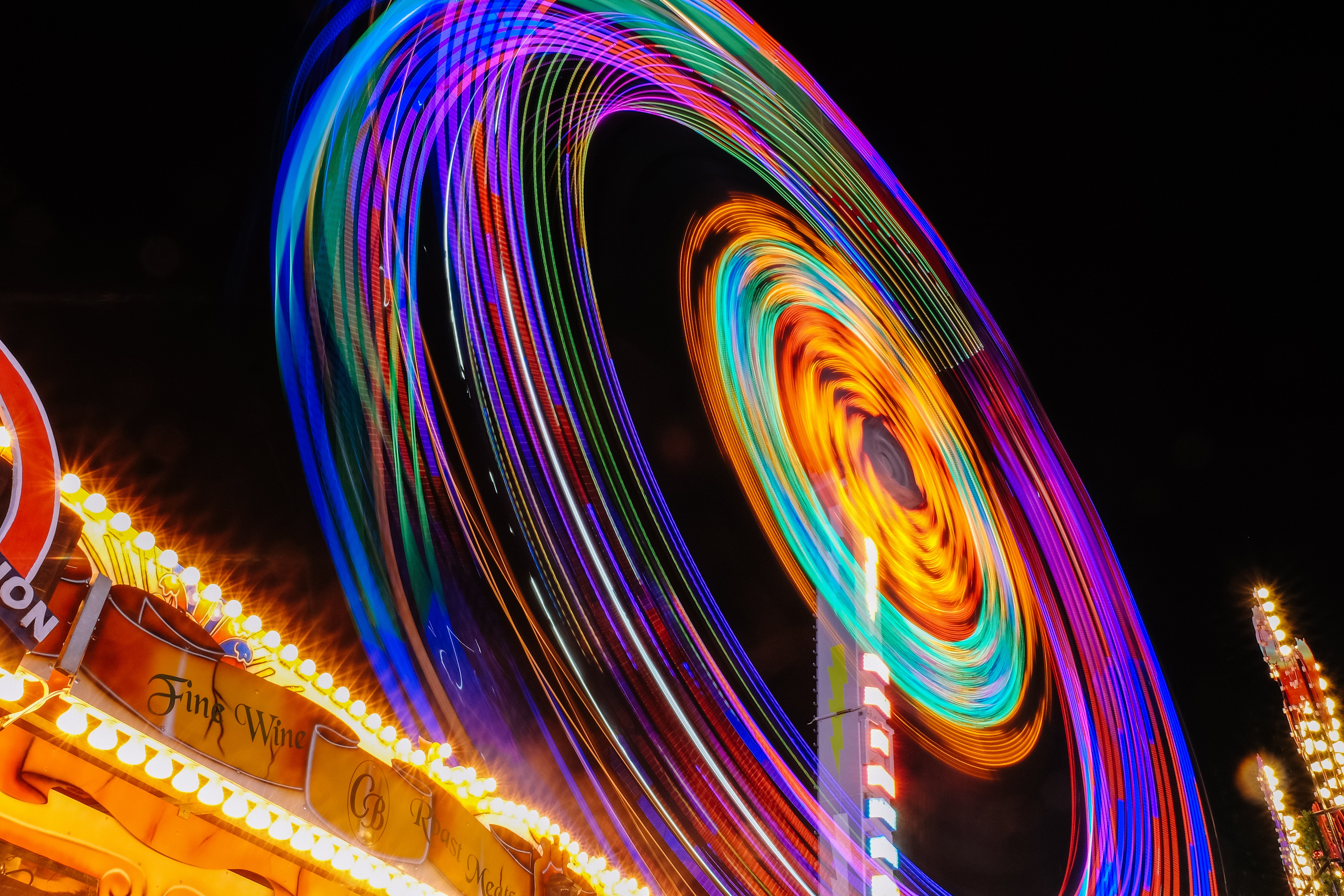 Time lapse of a ferris wheel at night creating circles of neon colors
